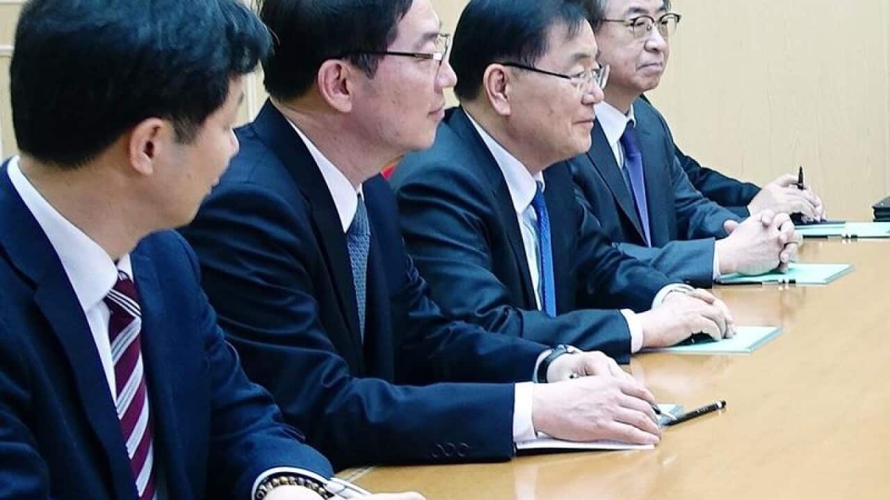 South and North Korean officials speak around a table.