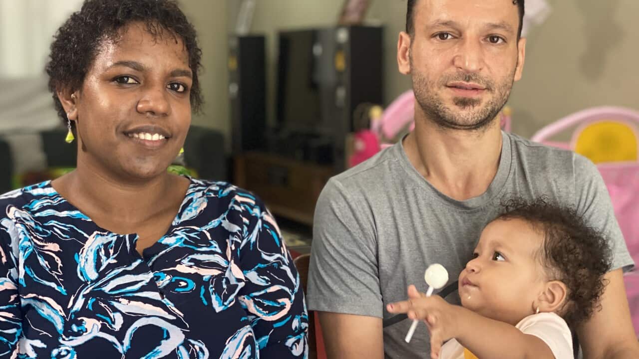 A man, a woman and a baby sitting together