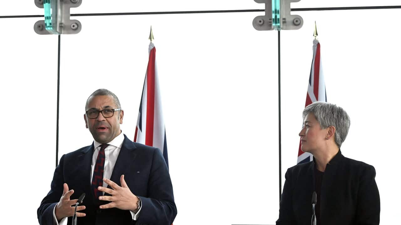 UK Foreign Secretary James Cleverly and Australia's Foreign Minister Penny Wong sit side by side in front of their respective flags
