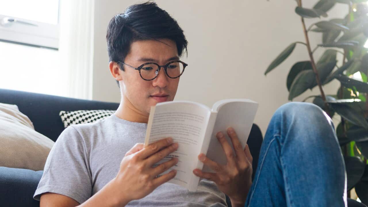 Young Man Reading Book At Home