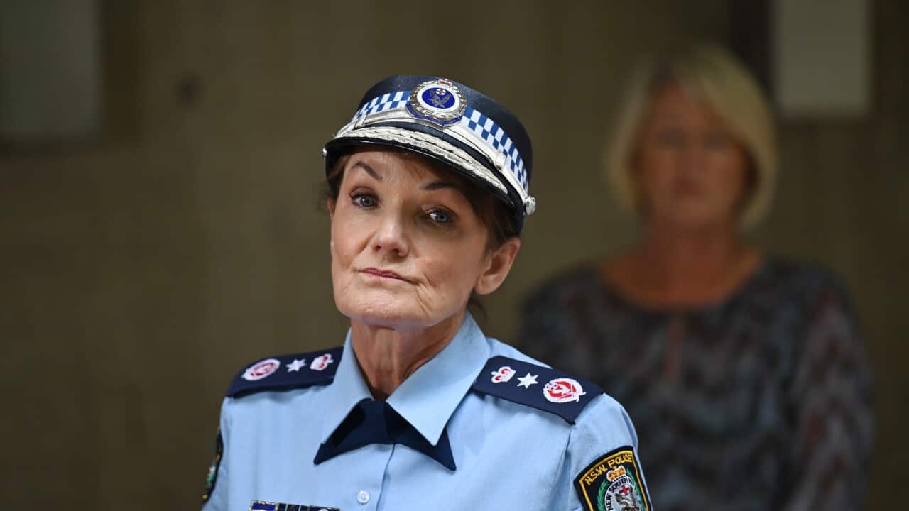 A woman in a blue police uniform looks at the camera at a press conference.