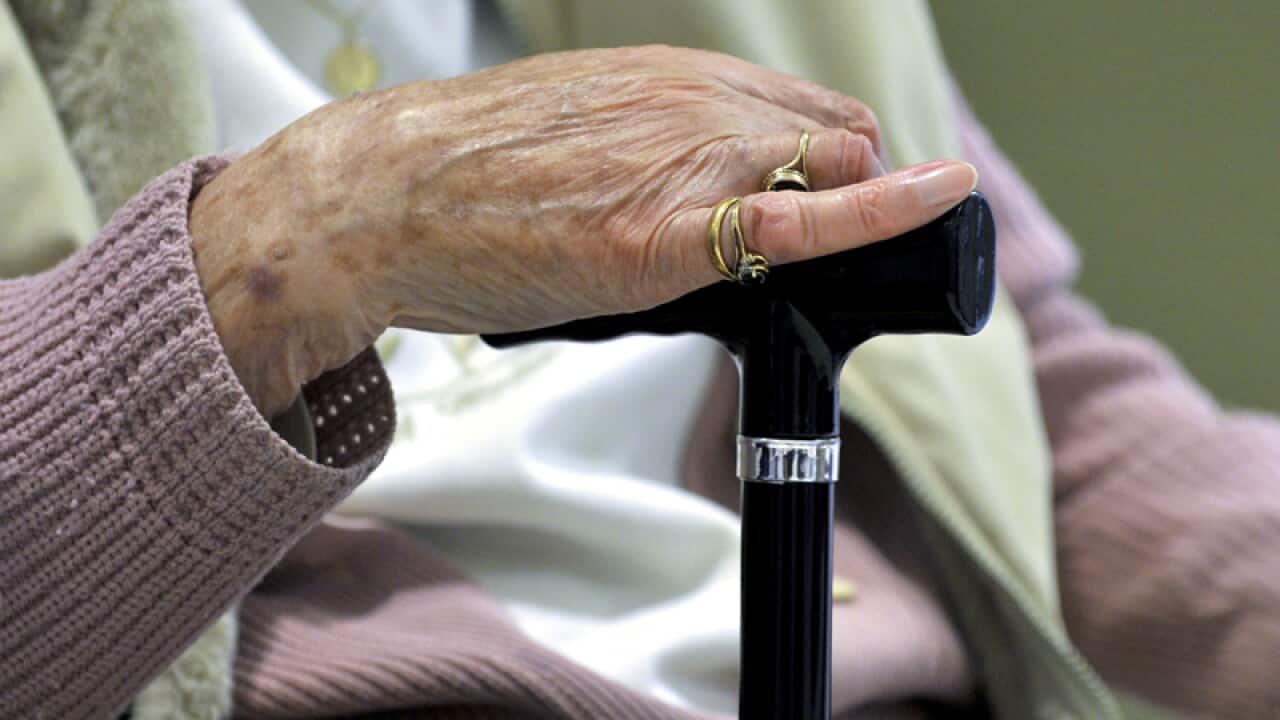 A woman uses a walking stick to assist he mobility