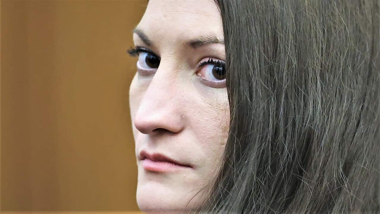 A close up of a younger white woman with dark brown hair looking at the camera.