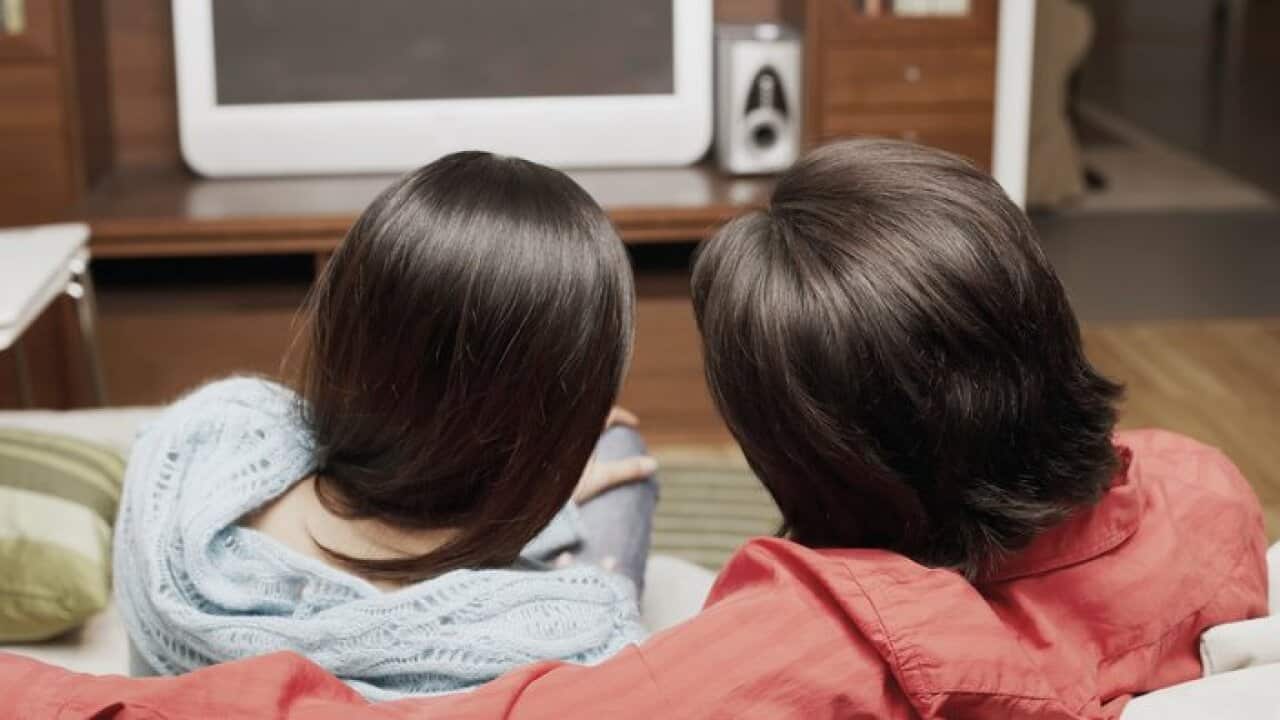 Rear view of a young couple watching television
