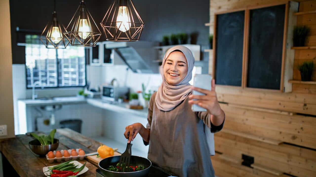 Mwanamke aandaa chakula cha Eid akitazama simu