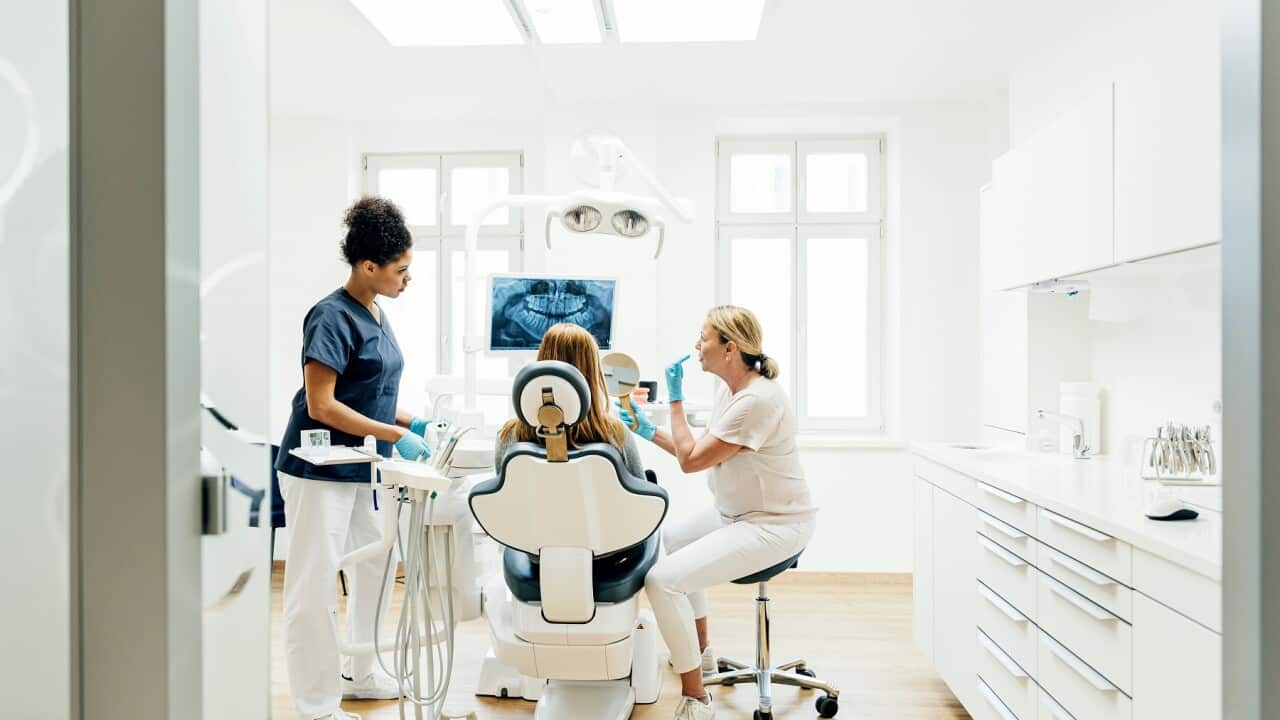 Orthodontist Showing Patient X-Ray Of Teeth In Surgery