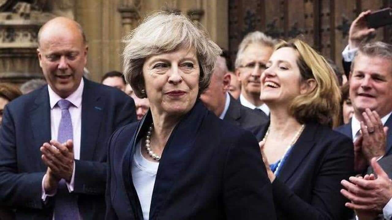 Britain's Theresa May is applauded by Conservative Party members of parliament outside the Houses of Parliament in London. (AAP)