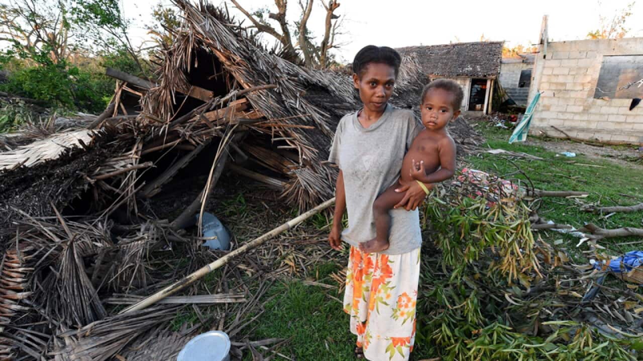 A woman holds her son in front of their home on Tanna, Vanuatu