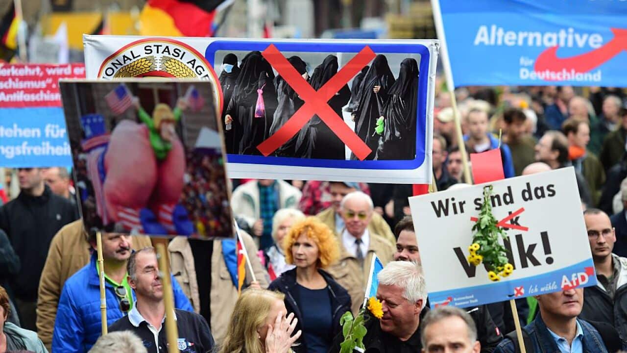 A supporter of the right-wing populist Alternative for Germany (AfD) party displays a placard showing crossed out Niqabs during a demonstration against the German government's asylum policy organized by the AfD party in Berlin on November 7, 2015.