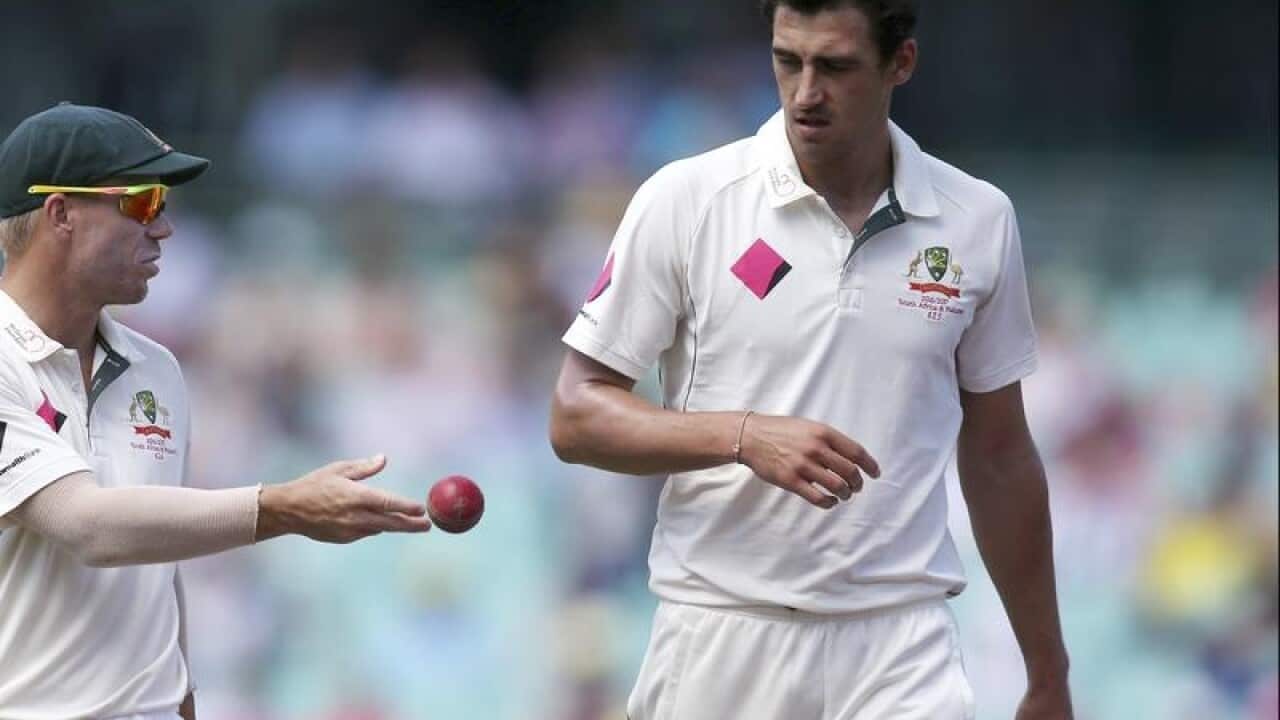 Australia's David Warner tosses the ball to teammate Mitchell Starc