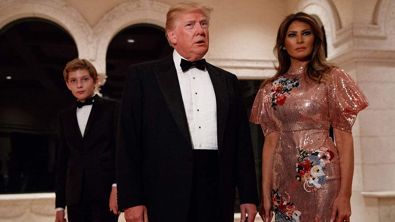 President Donald Trump, speaks with reporters as he arrives for a New Year's Eve gala with first lady Melania Trump and their son Barron.
