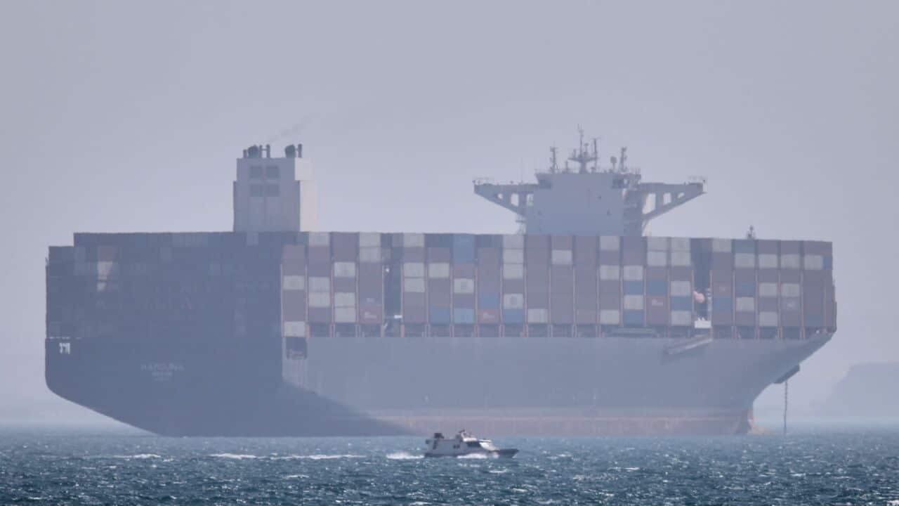 A container ship sits at anchor as a small motorboat passes in the foreground in the Strait of Hormuz off Bandar Abbas, Iran, Saturday, May 2, 2026. (Amirhosein Khorgooi-ISNA via AP).