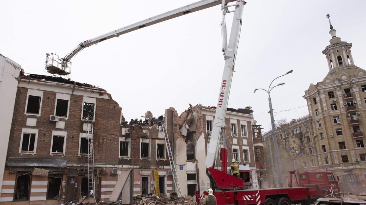 Rescue workers cleaning up rubble in front of demolished buildings