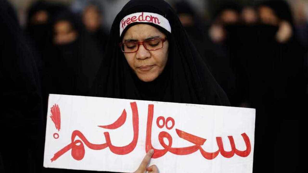 A Bahraini anti-government protester holds a banner in Arabic that reads "damn you" during a demonstration against Saudi Arabia's execution of Shiite cleric Sheikh Nimr al-Nimr, in Daih, Bahrain