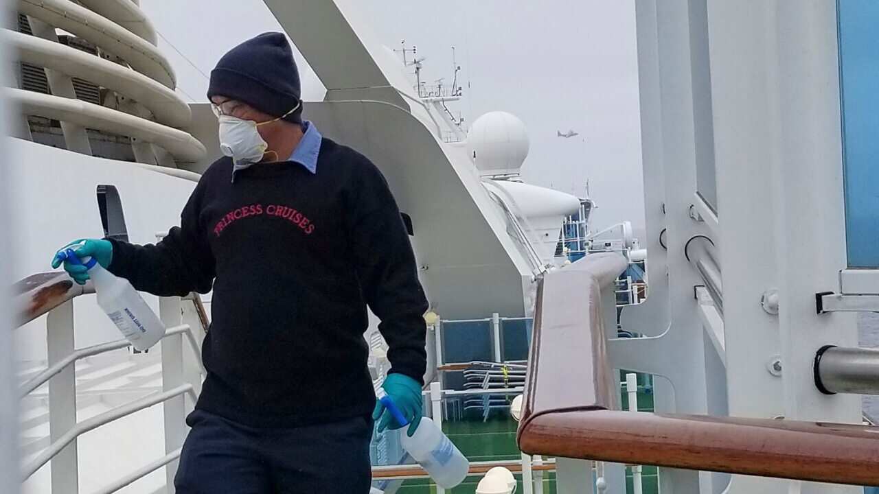 A cruise ship worker cleans a railing on the Grand Princess off the California coast