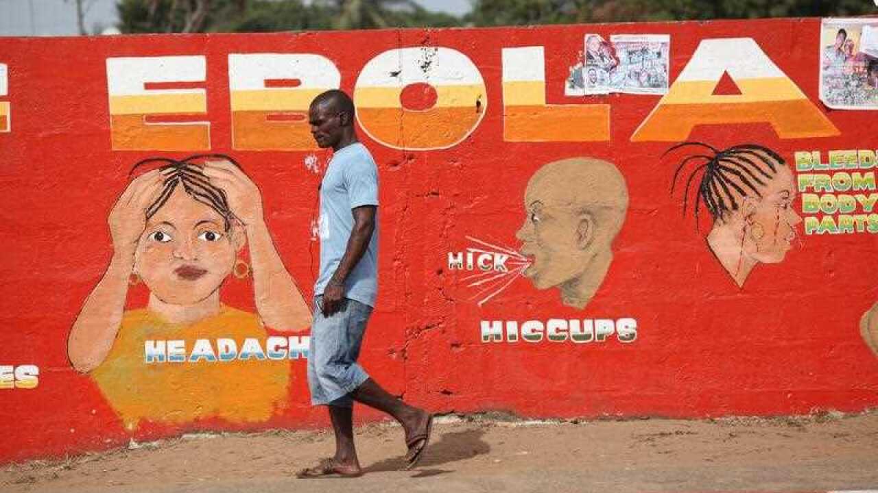 A Liberian man walks past an Ebola awareness painting on a wall in downtown Monrovia, Liberia.
