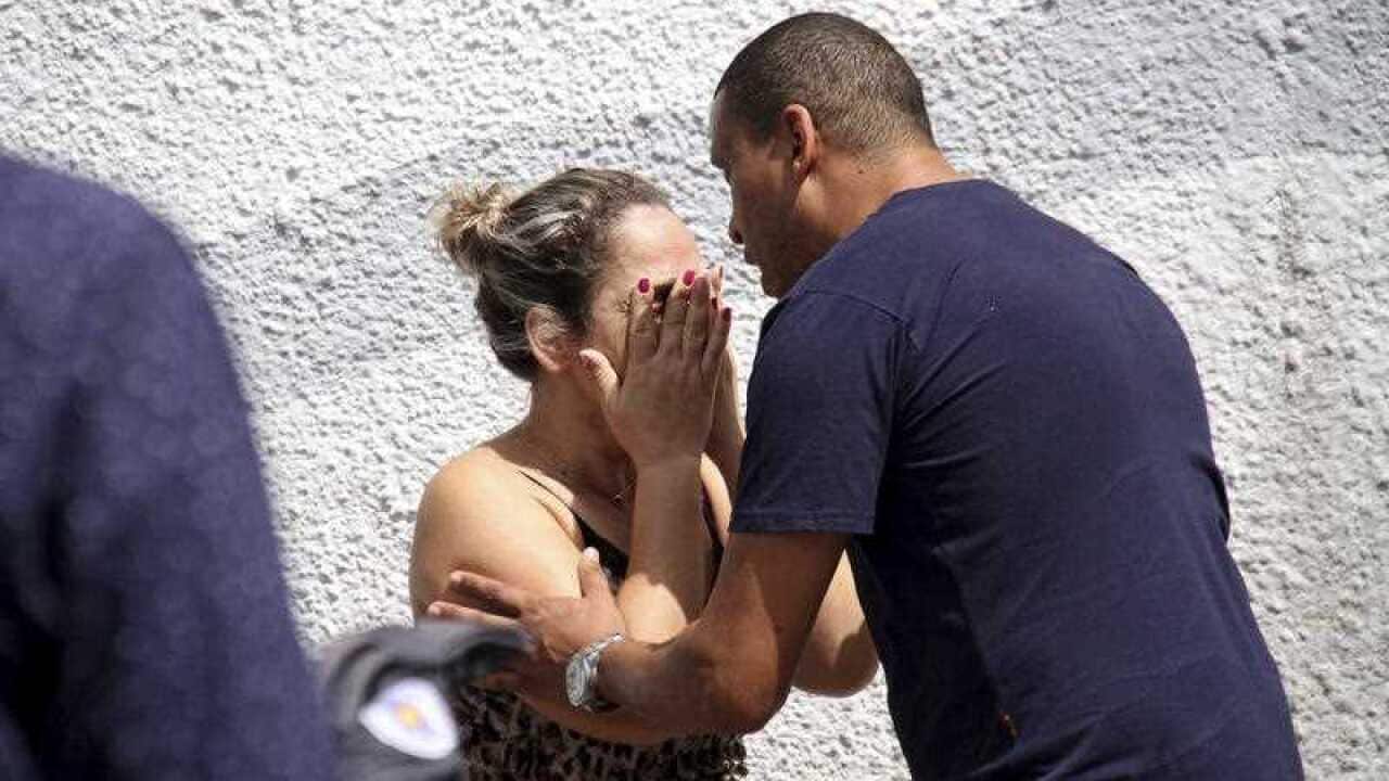 A man comforts a woman at the Raul Brasil State School after the shooting.