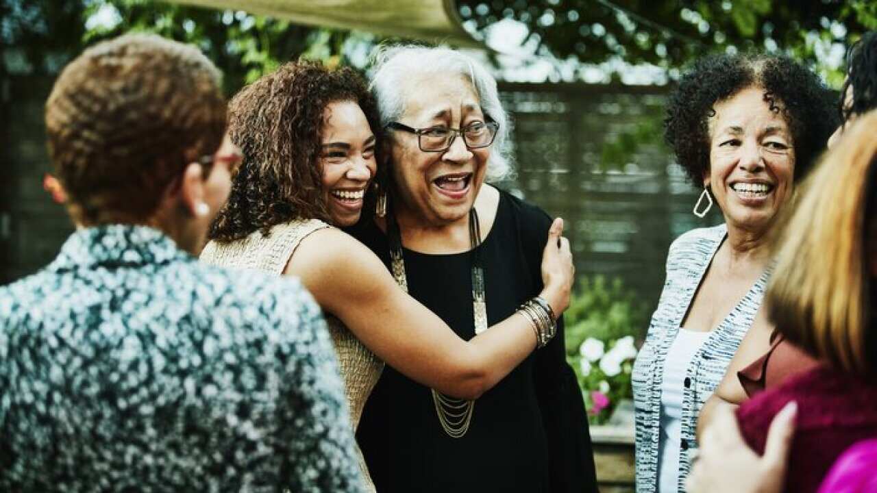 Mature daughter embracing senior mother after outdoor family dinner party