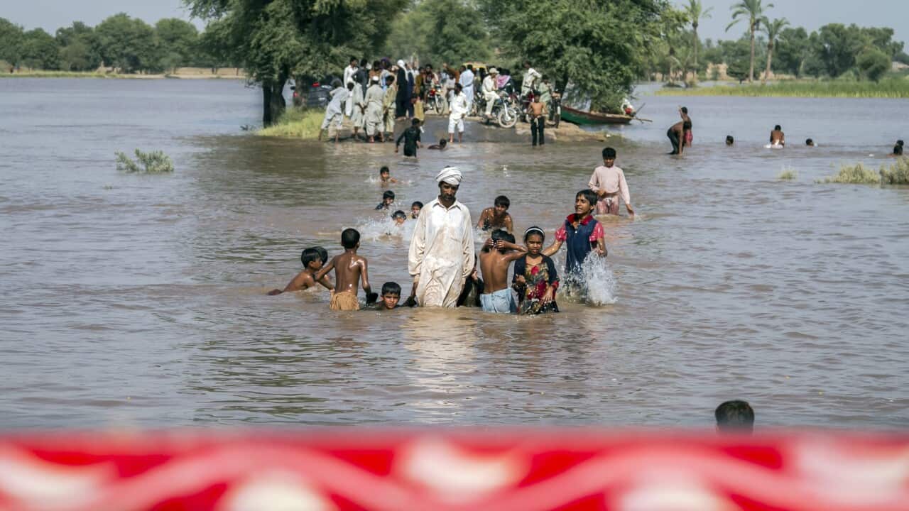 People cross a road submerged in floods in Shujabad, on the outskirts of Multan, Pakistan, 14 September 2014. (EPA/OMER SALEEM)