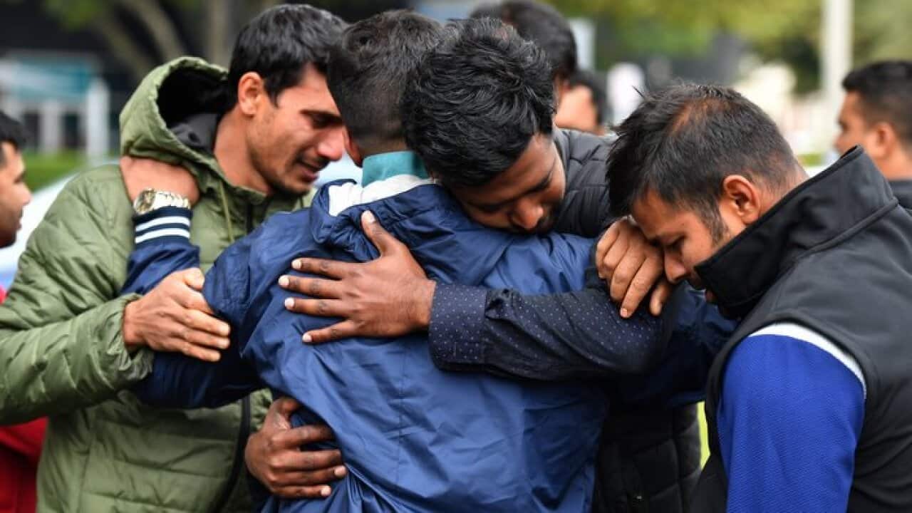 Friends of a missing man grieve outside a refuge centre in Christchurch, Sunday, March 17, 2019