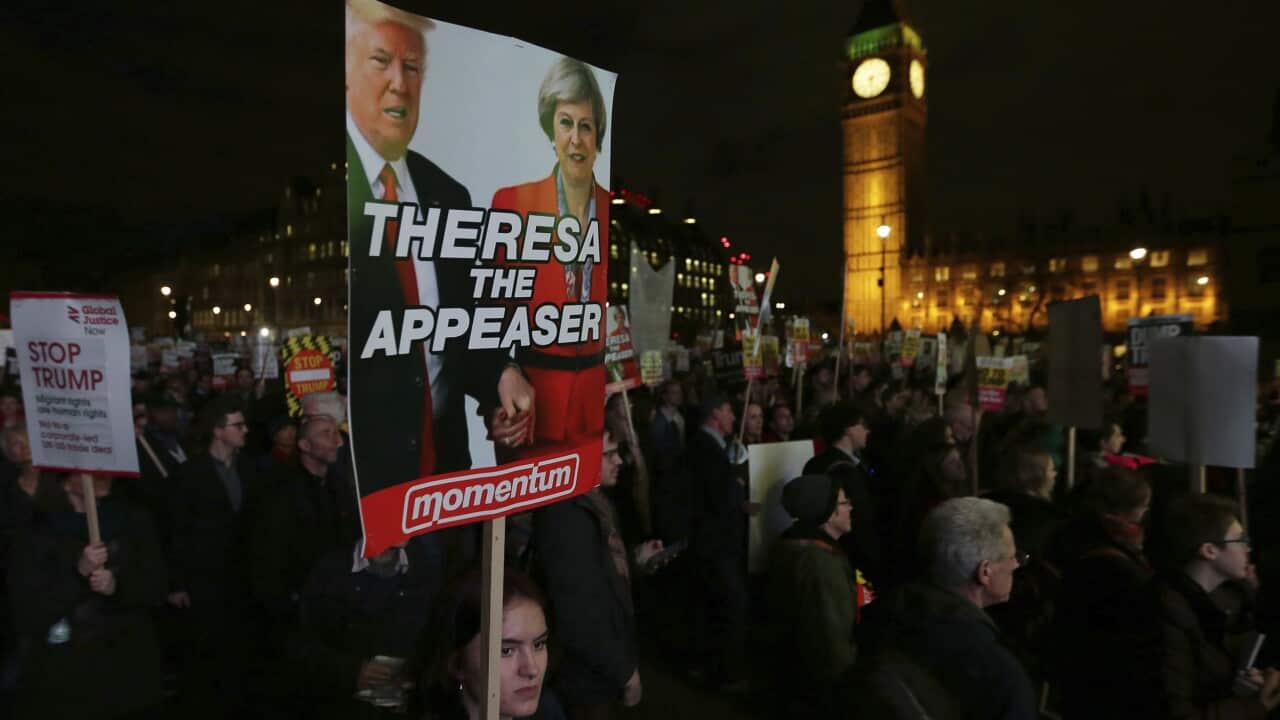 Demonstrators hold placards as they listen to speeches during a rally in Parliament Square opposing US President Donald Trump