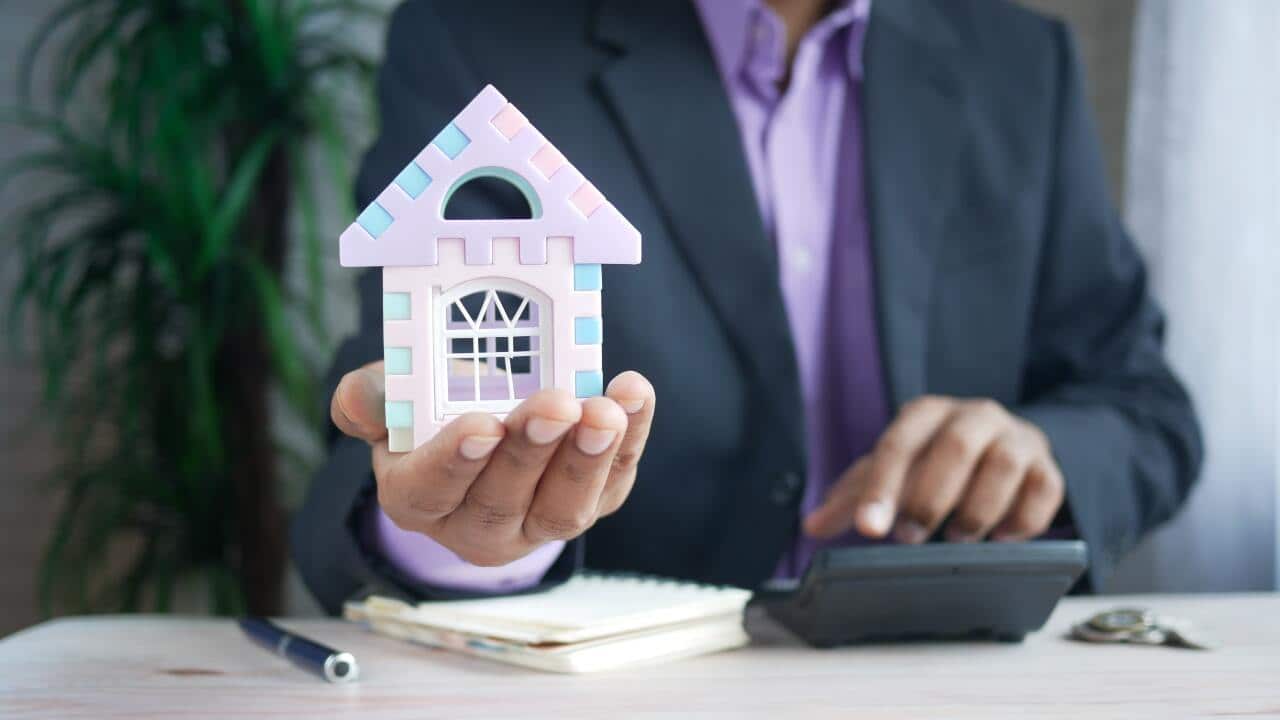 the concept of finance concept , man holding house in hand .