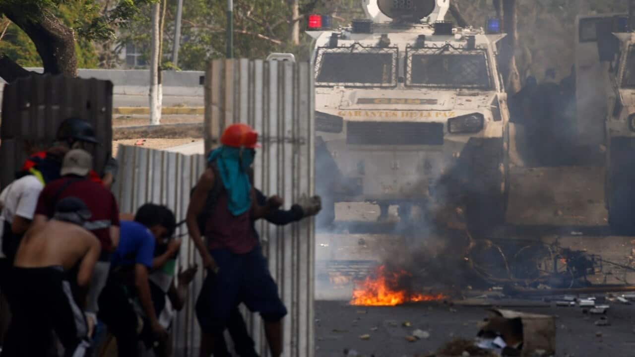 Opponents to Venezuela's President Nicolas Maduro stand behind makeshift shields as they face off with Bolivarian National Guards