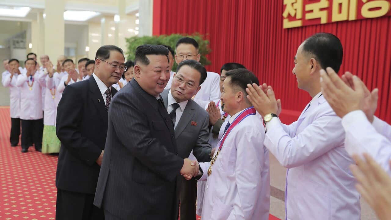 North Korean leader Kim Jong Un shakes hands with a health official.