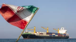 An Iranian flag in the wind with an oil tanker in the background.
