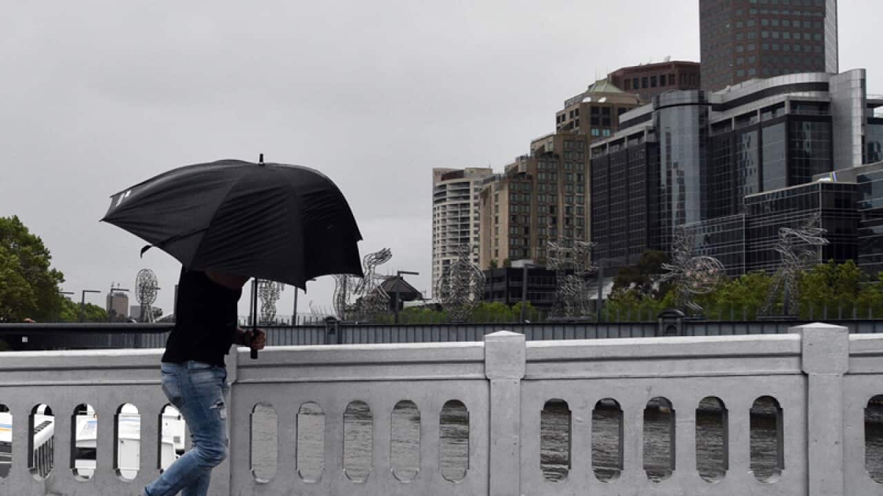 A man crosses Queen Street Bridge as strong winds hit