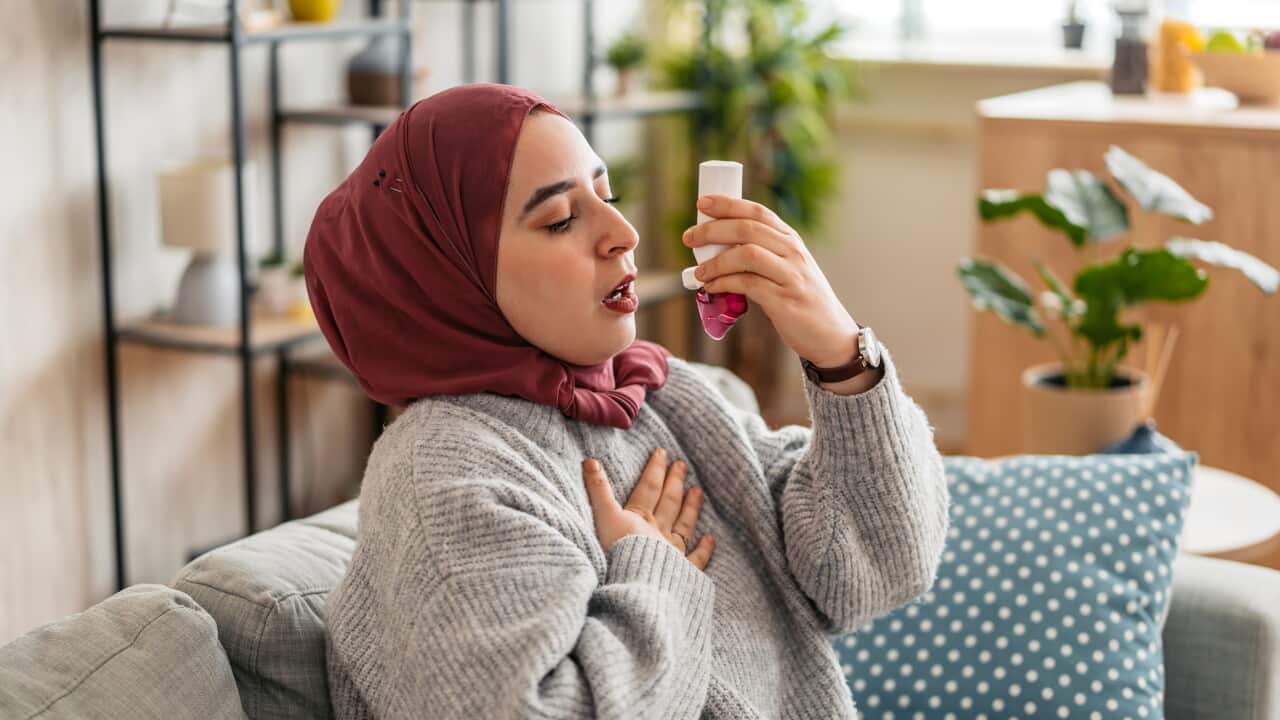 Young Muslim Woman Taking Asthma Inhaler While Sitting On The Sofa At Home