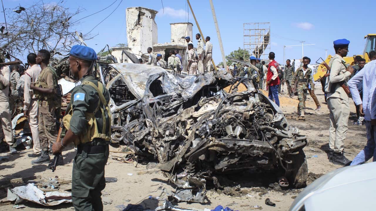 Security officers gather at the scene of a large explosion near a checkpoint in Mogadishu, Somalia.