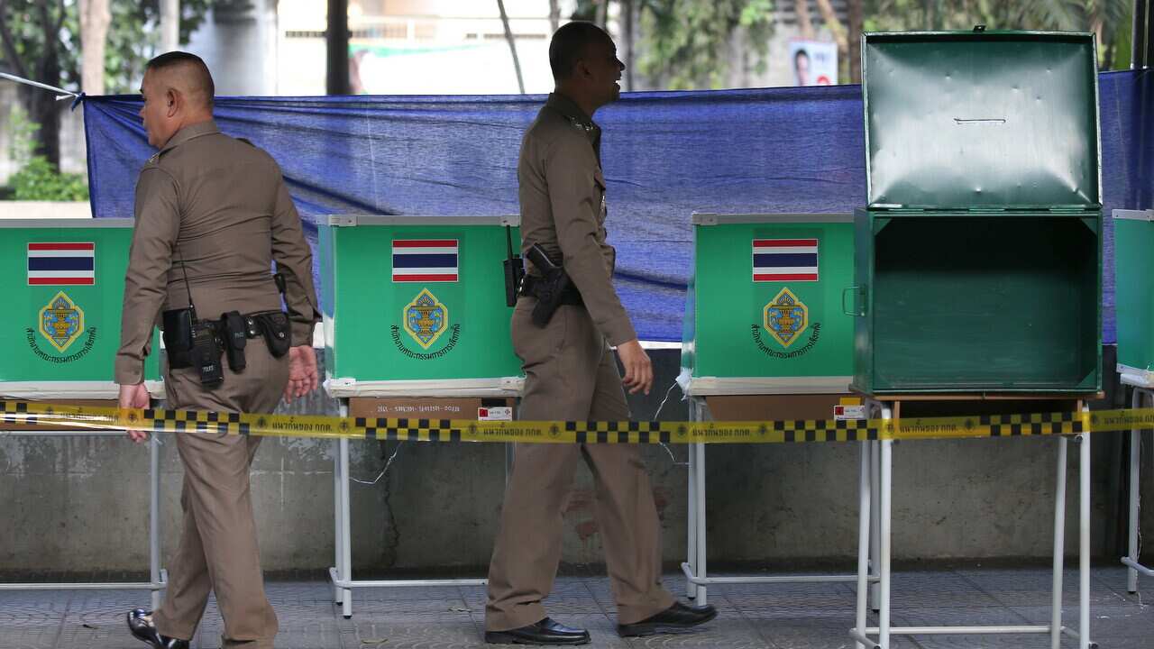 Thai police officers check the setup of a ballot boxes before voting starts at a polling station for the general election in Bangkok.
