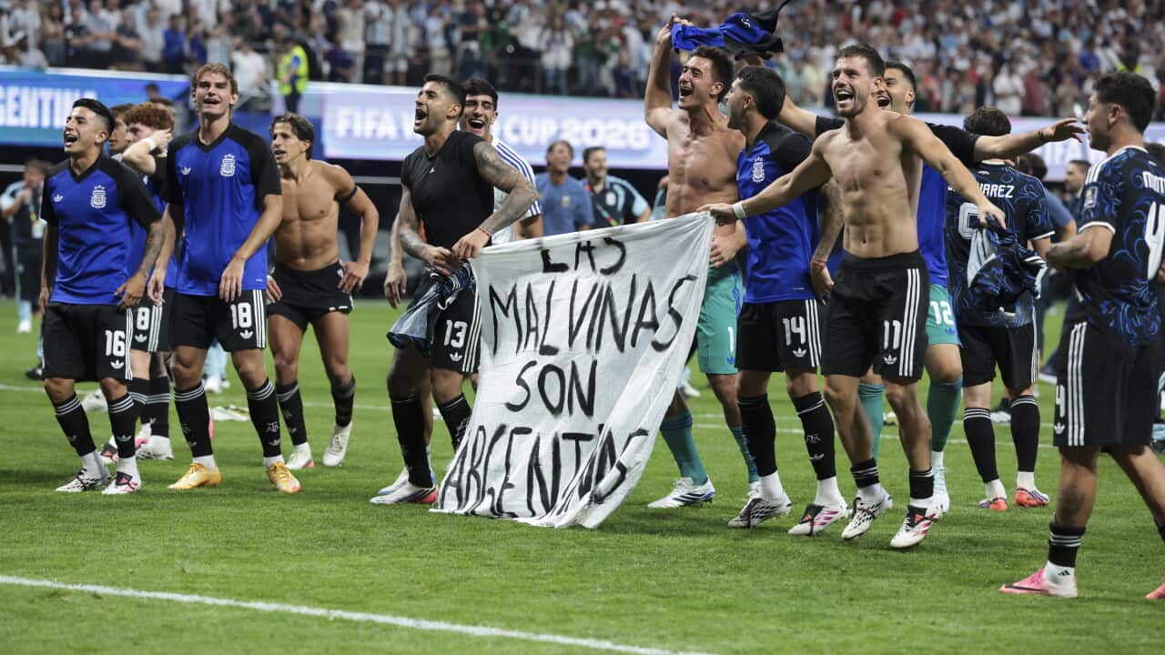 Argentinian football players celebrating on a football pitch. Some are holding a banner that reads, in Spanish, "The Falkland Islands are Argentinian".
