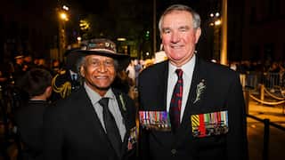 Two men wearing war medals smiling.