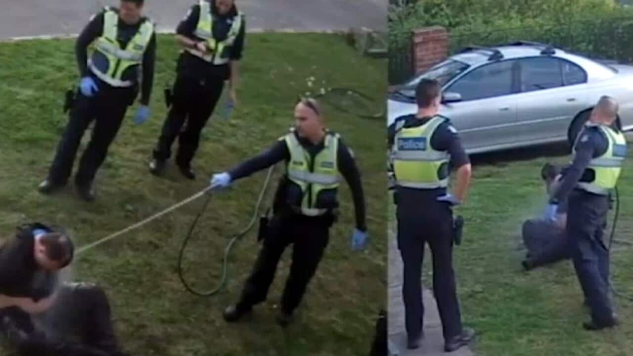 A screenshot from a CCTV video, showing police pepper spraying the man