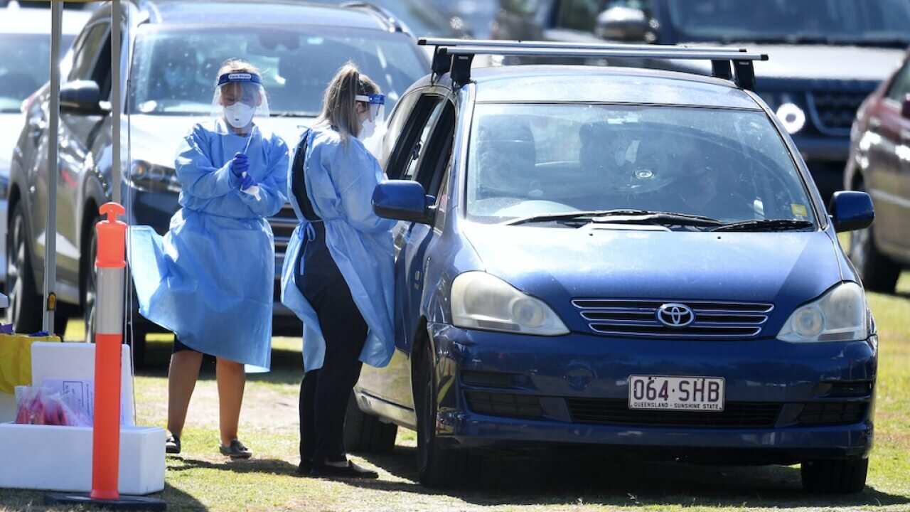 Health workers swab members of the public at a pop-up COVID-19 testing station at Indooroopilly State High School in Brisbane