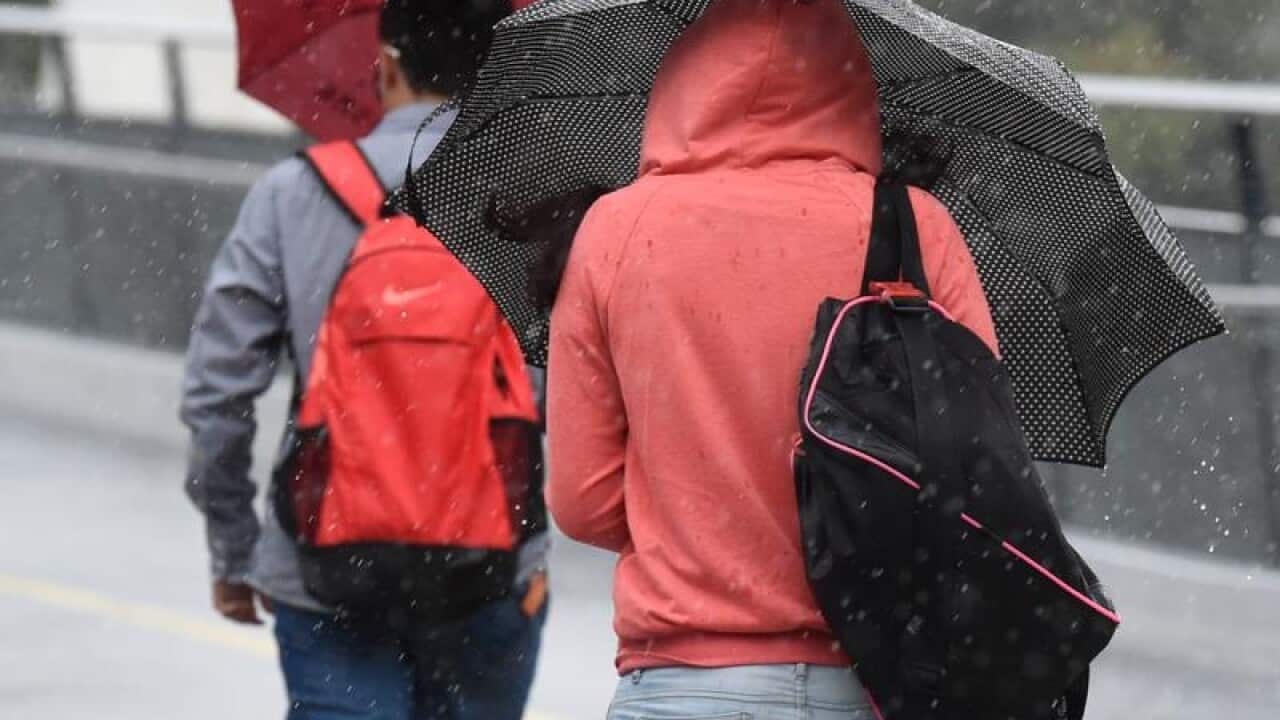 Pedestrians walk through rainy weather.