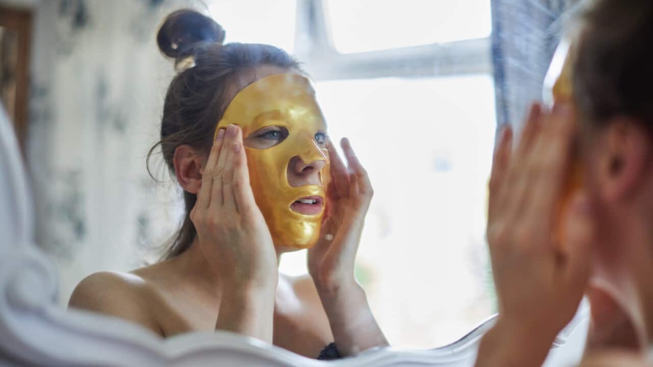 Woman looking in a mirror putting a face mask on