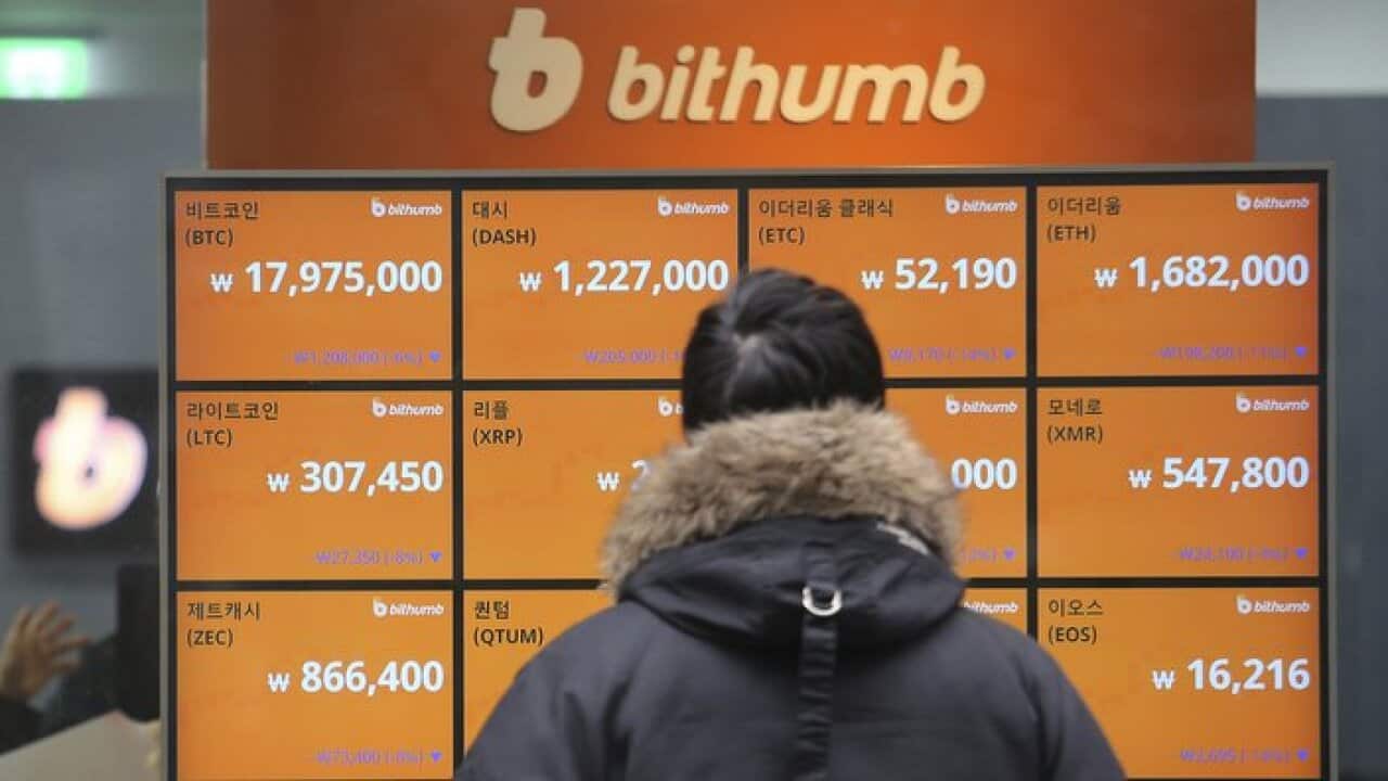 A man watches a screen showing the prices of bitcoin
