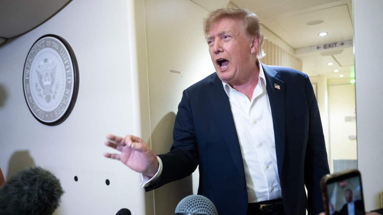A man wearing a suit speaks to the media