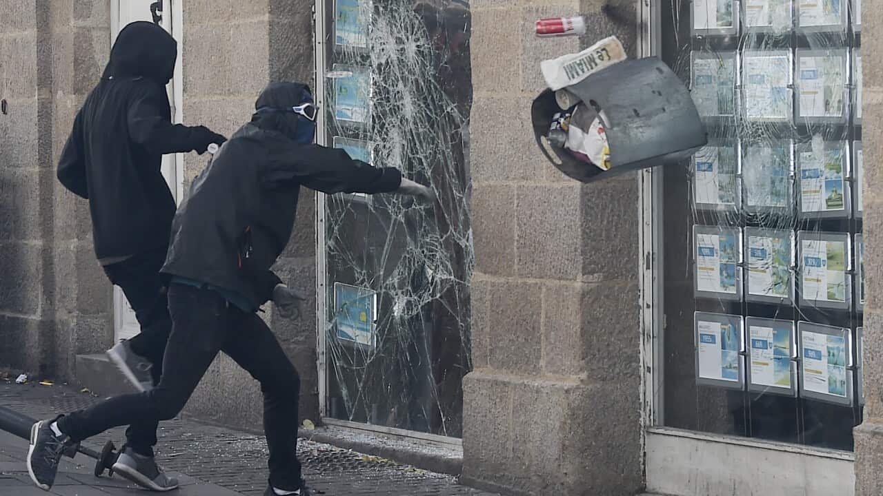 Protestors break the window of a shop on the sideline of an anti-government demonstration called by the "Yellow Vests" movement in Nantes, western France.