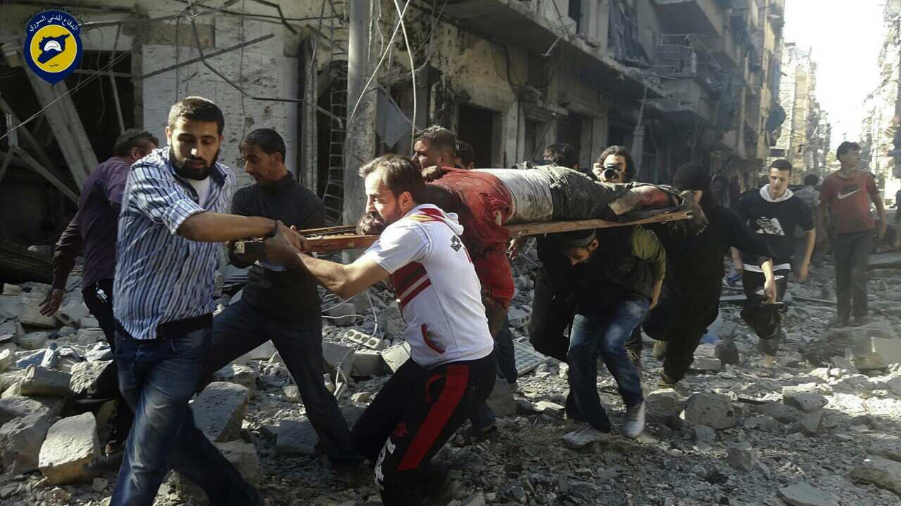 Syrians hold a victim after airstrikes by government helicopters on the rebel-held Aleppo neighborhood of Mashhad, Syria, Tuesday Sept. 27, 2016