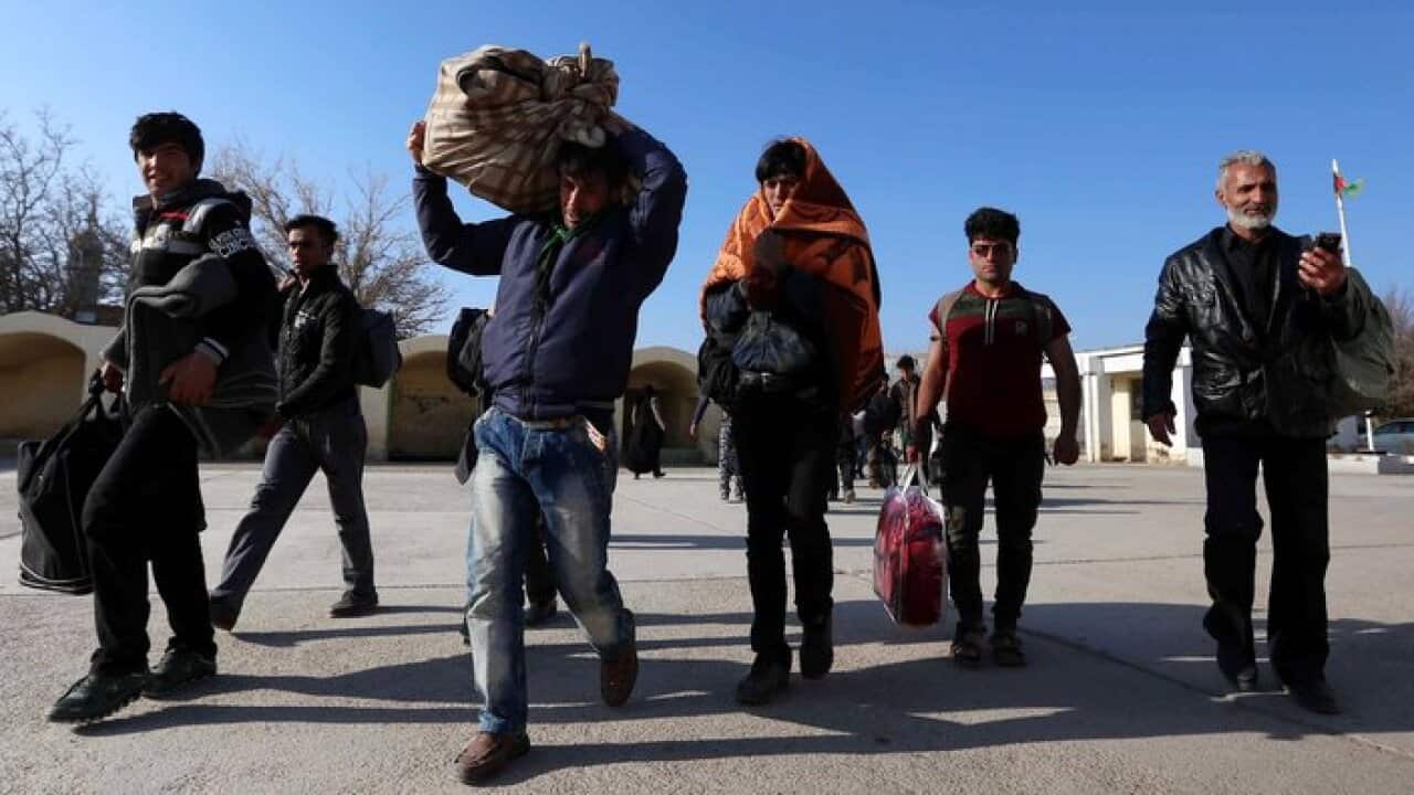 Afghan refugees cross the border into Afghanistan, after they were deported by Iran