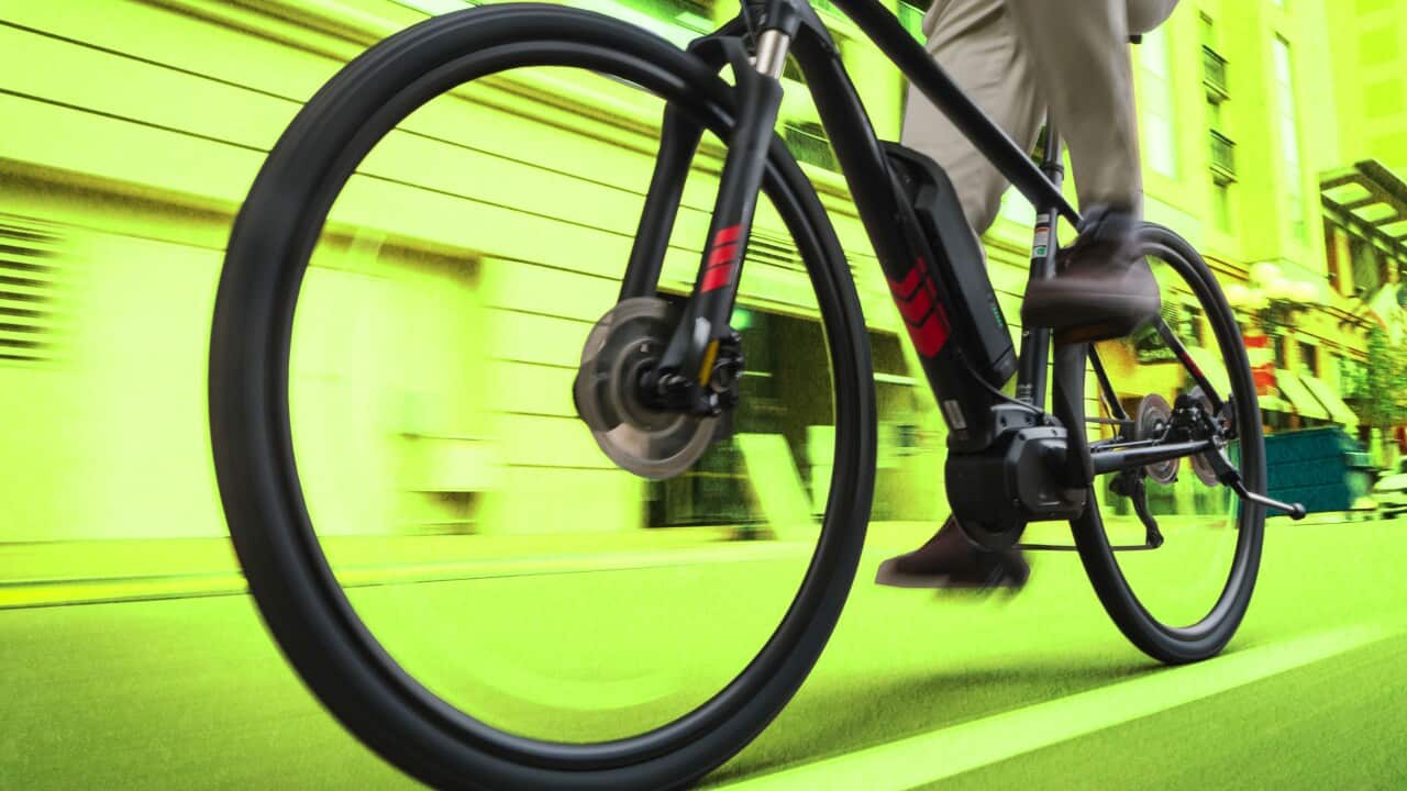An ebike is being ridden in a street with motion with a green background