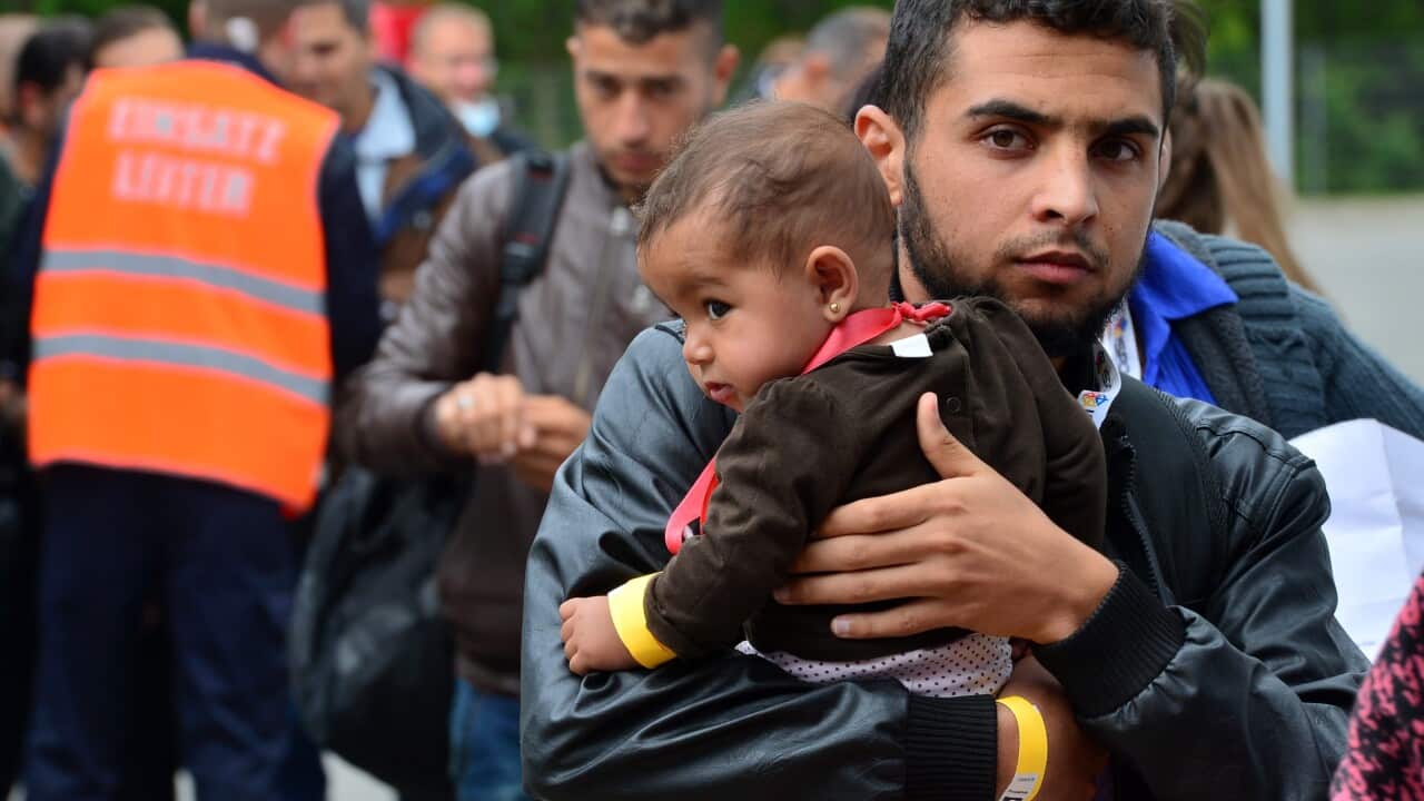 A refugee carries a child as they arrive at the exhibition centre in Erfurt, Germany.