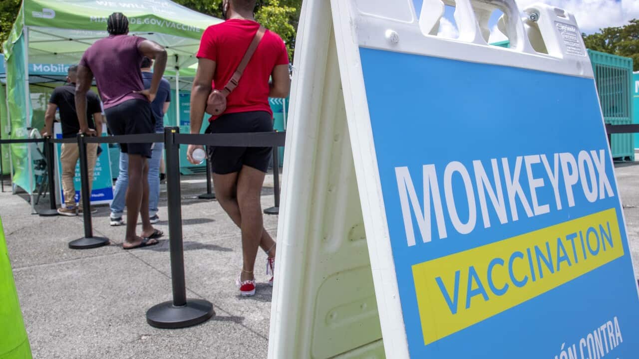 Monkeypox vaccine sign with people lined up at tent