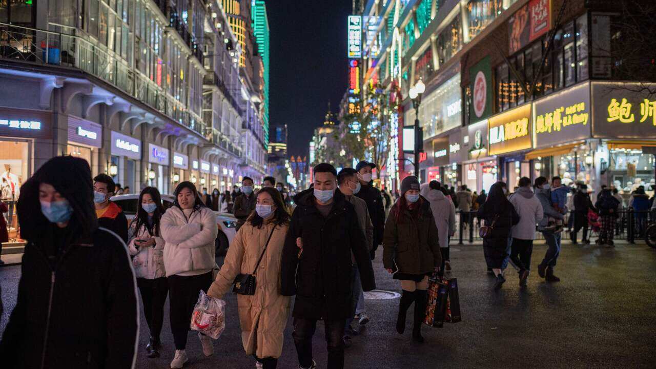 People wearing face masks walk on Jianghan street in Wuhan on 10 January, 2021, the eve of the first anniversary of China confirming its first COVID-19 death.