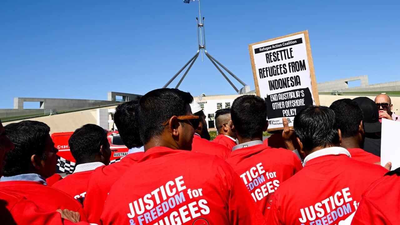 Refugee advocates with red T-shirts hold signs calling for an to Australia's offshore detention policy outside Parliament House in Canberra.