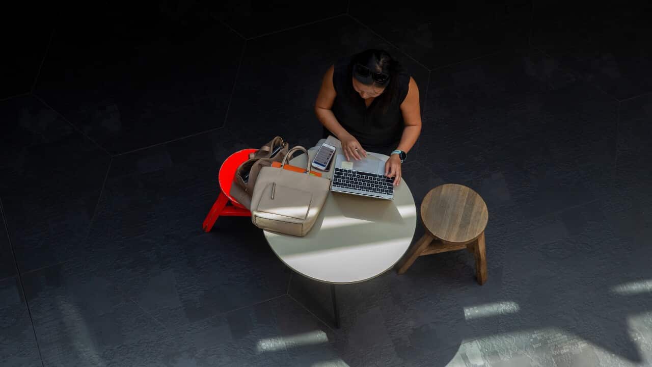 A woman works at a table on a laptop